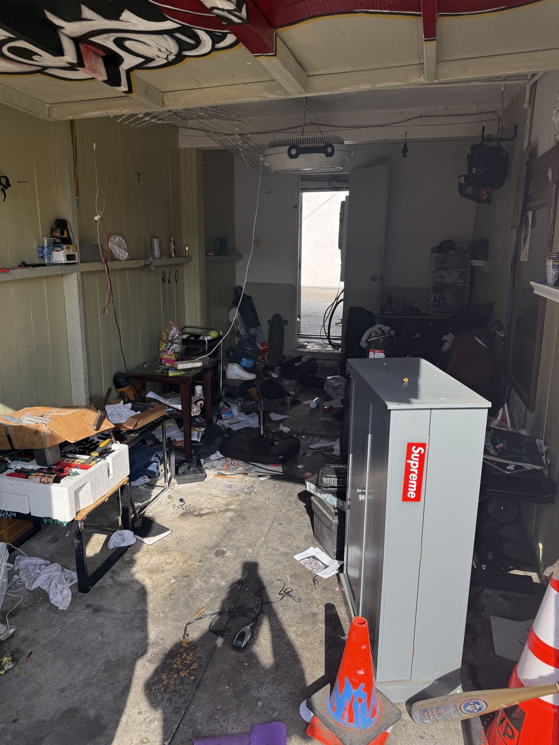 Damaged cluttered room with debris, broken ceiling, and a red utility cabinet in the foreground