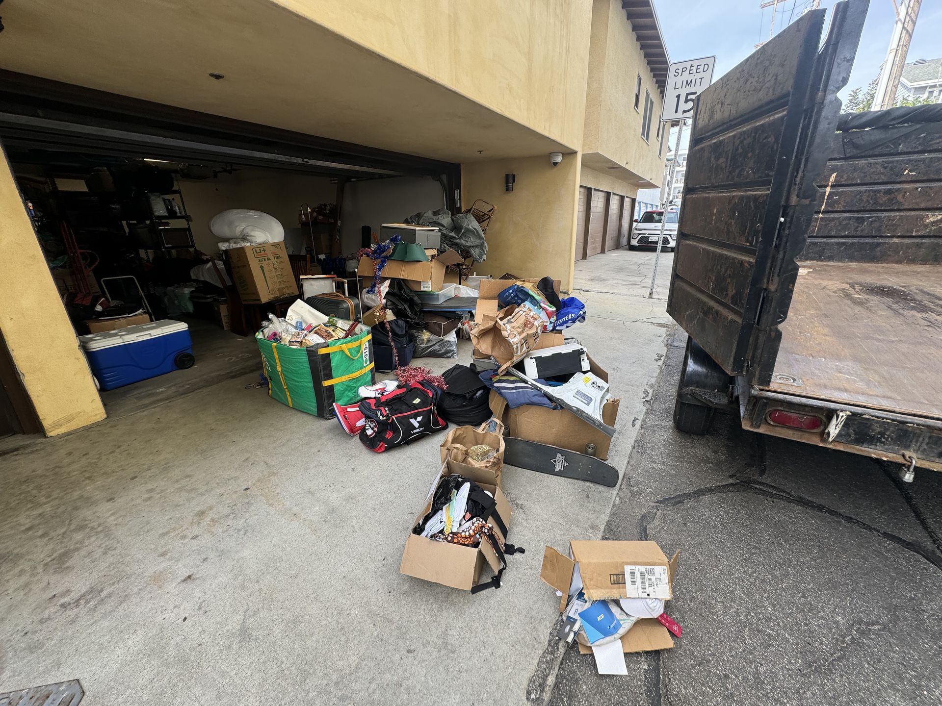 Piles of assorted boxes and debris in a garage area beside a truck and building.