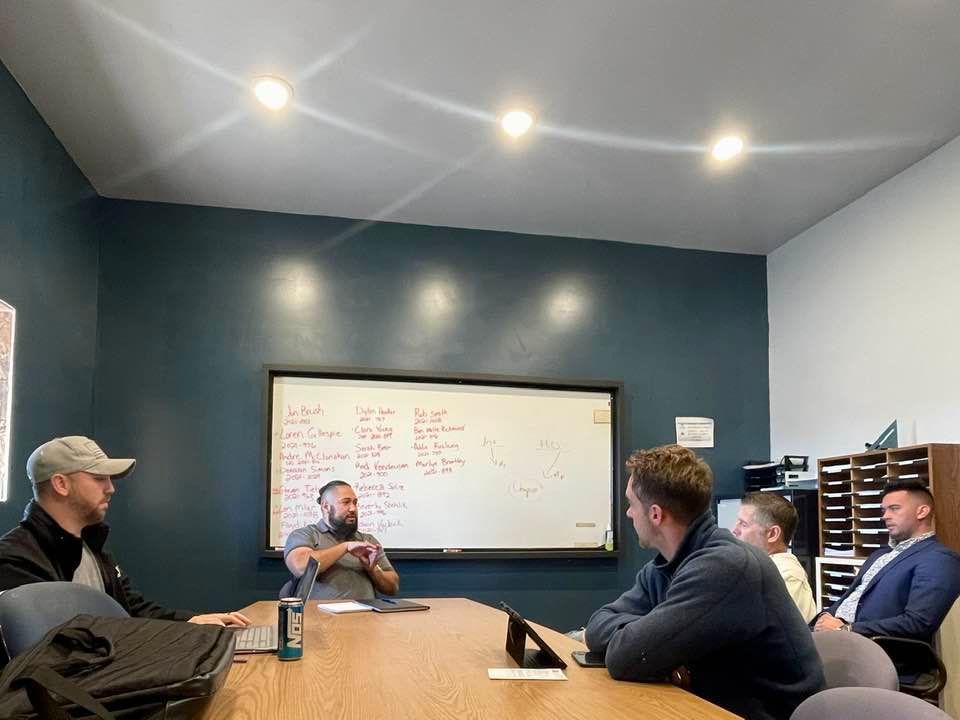 A group of men are sitting around a table in a conference room.