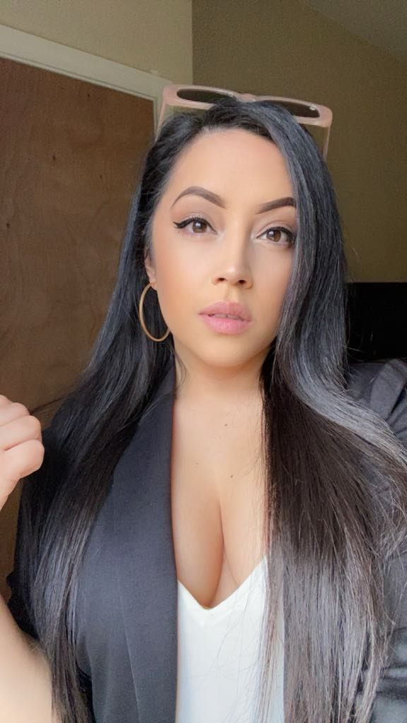 A woman with long black hair is wearing a white shirt and a black jacket.