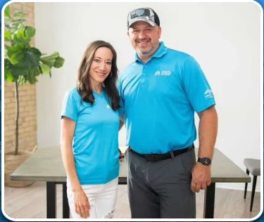 A man and a woman in blue shirts are posing for a picture