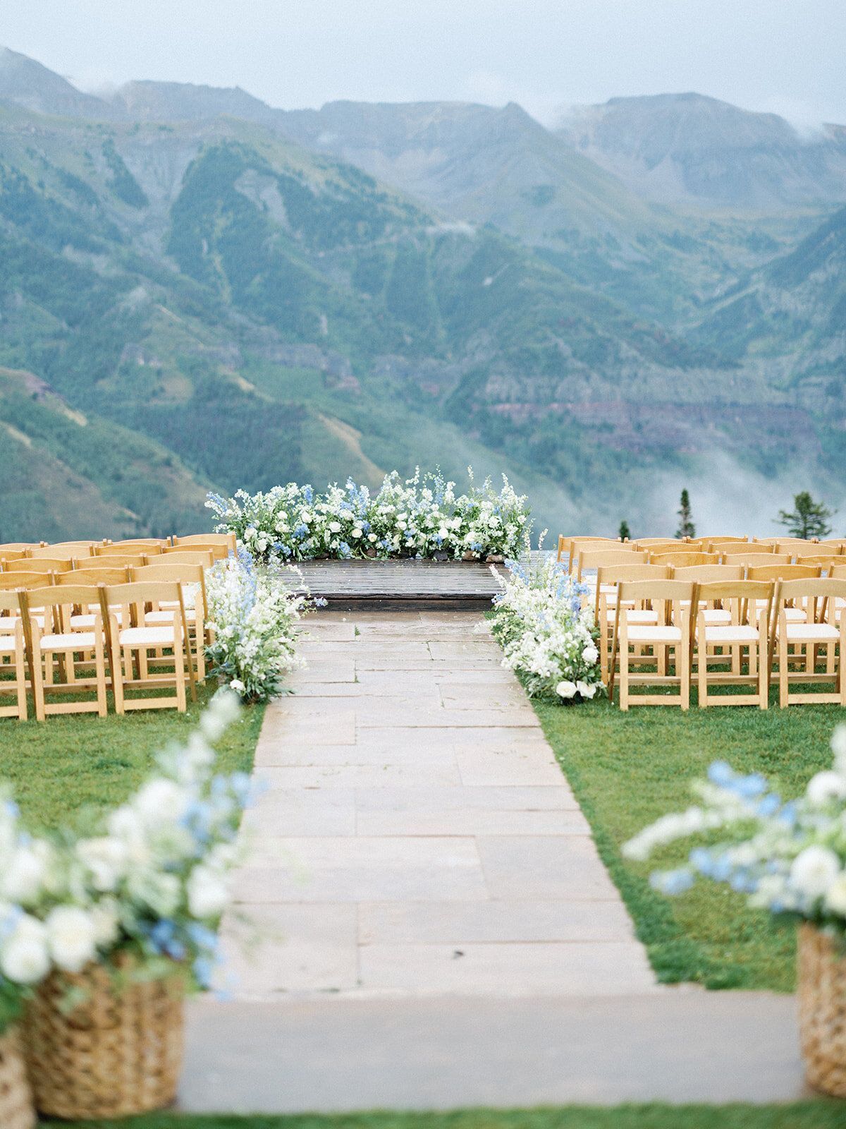 A wedding ceremony is taking place in the mountains with a view of the mountains.