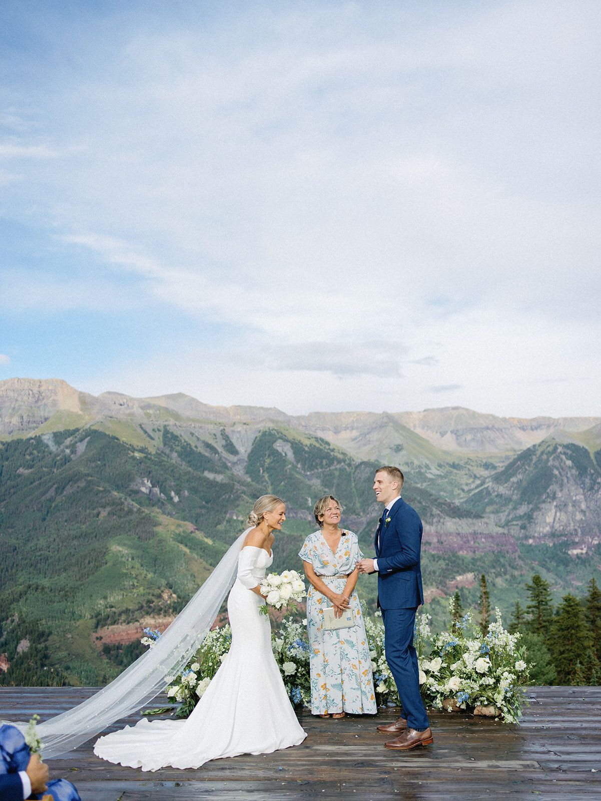 A bride and groom are getting married in front of a mountain range.