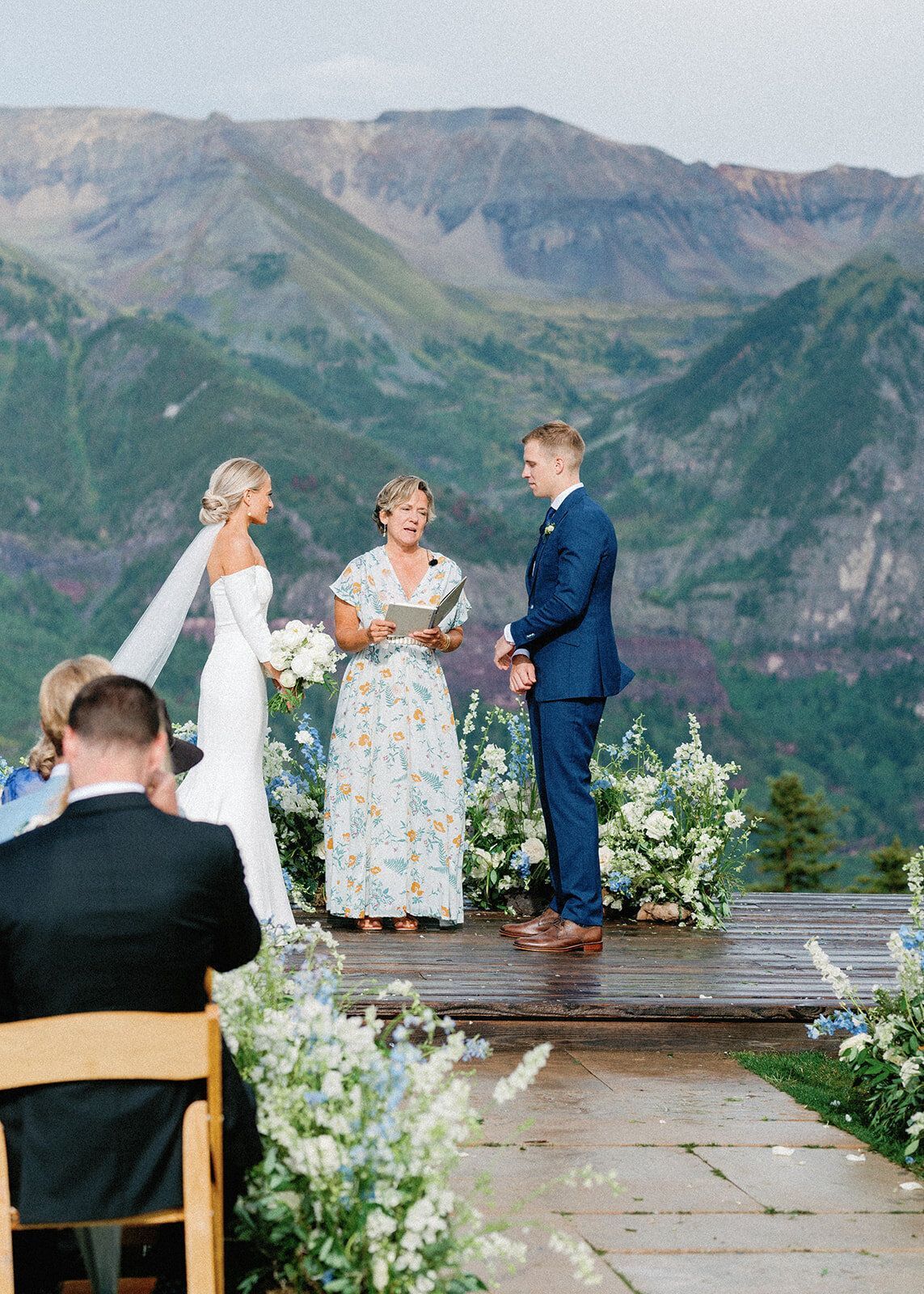 A bride and groom are getting married in front of a mountain range.