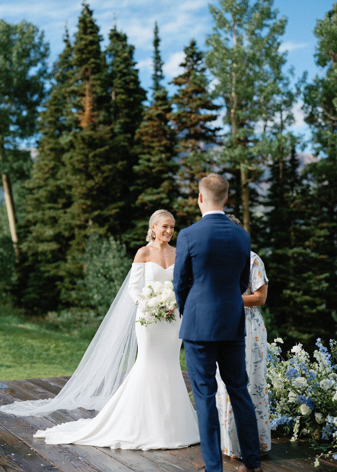 A bride and groom are standing on a wooden deck during their wedding ceremony.
