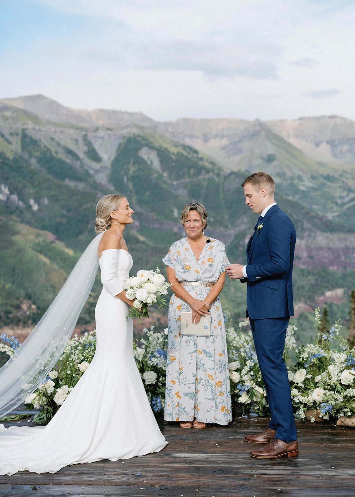 A bride and groom are getting married in front of a mountain range.