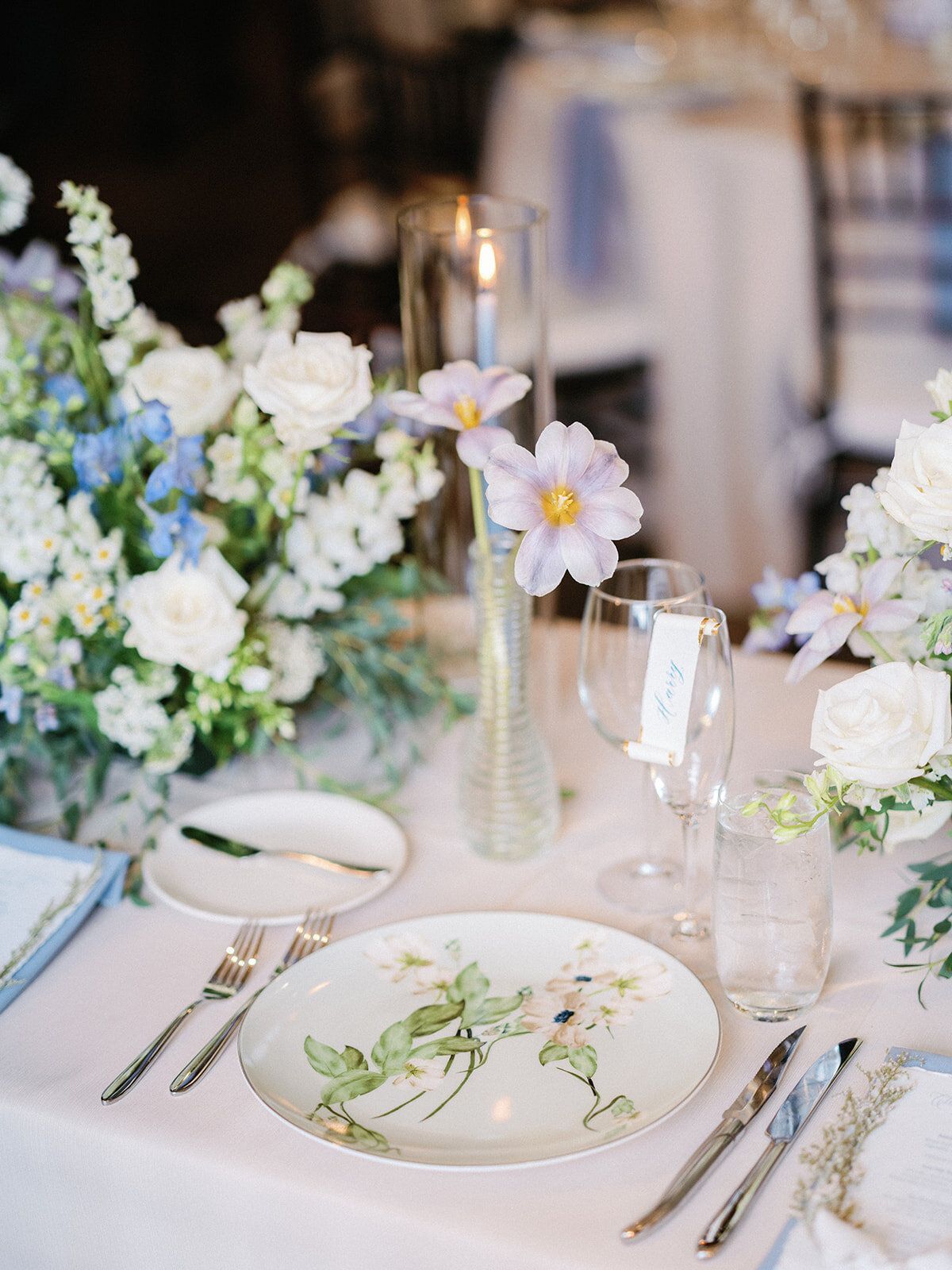 A table with plates , utensils , and flowers on it.