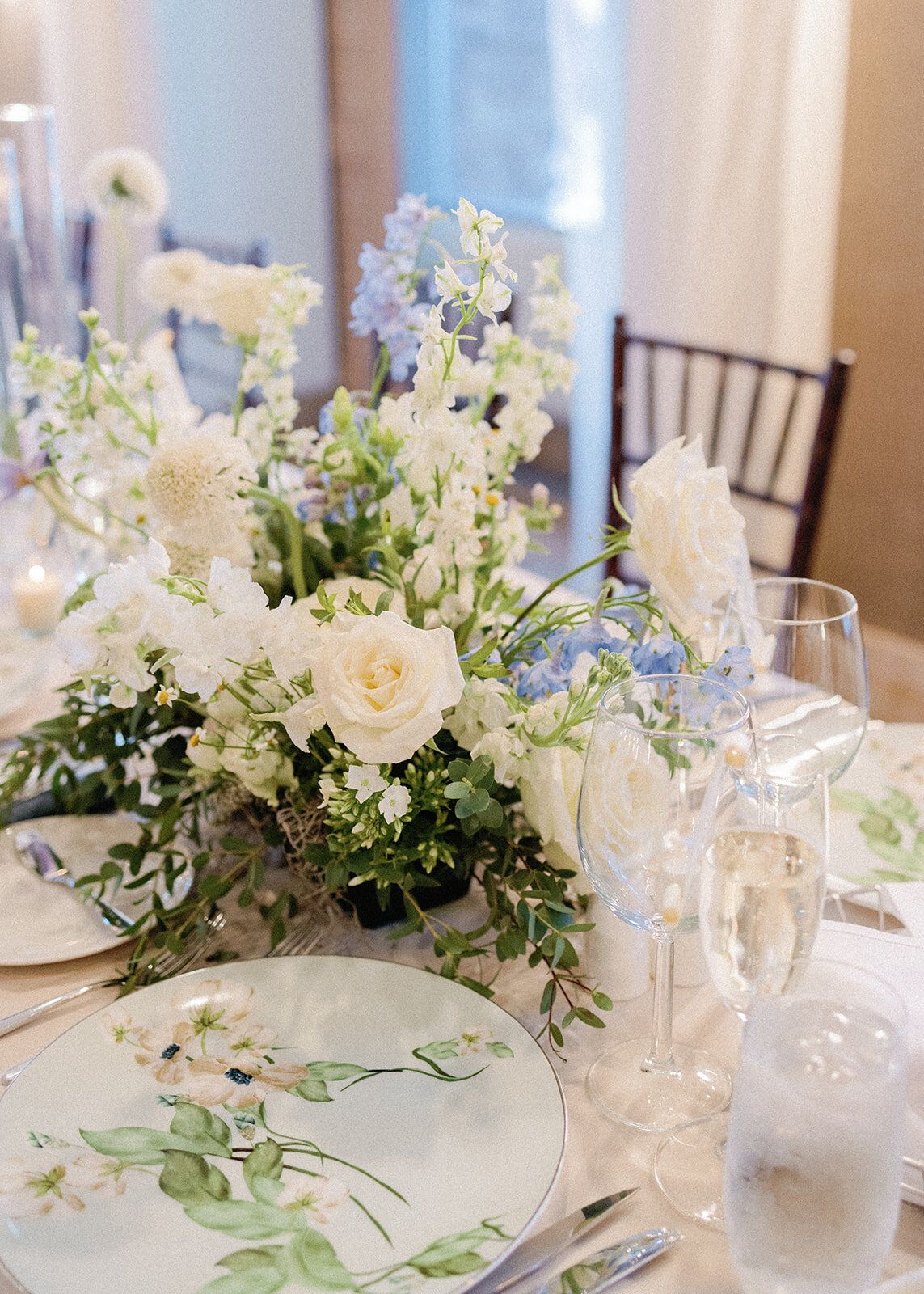 A table with plates , glasses , and flowers on it.