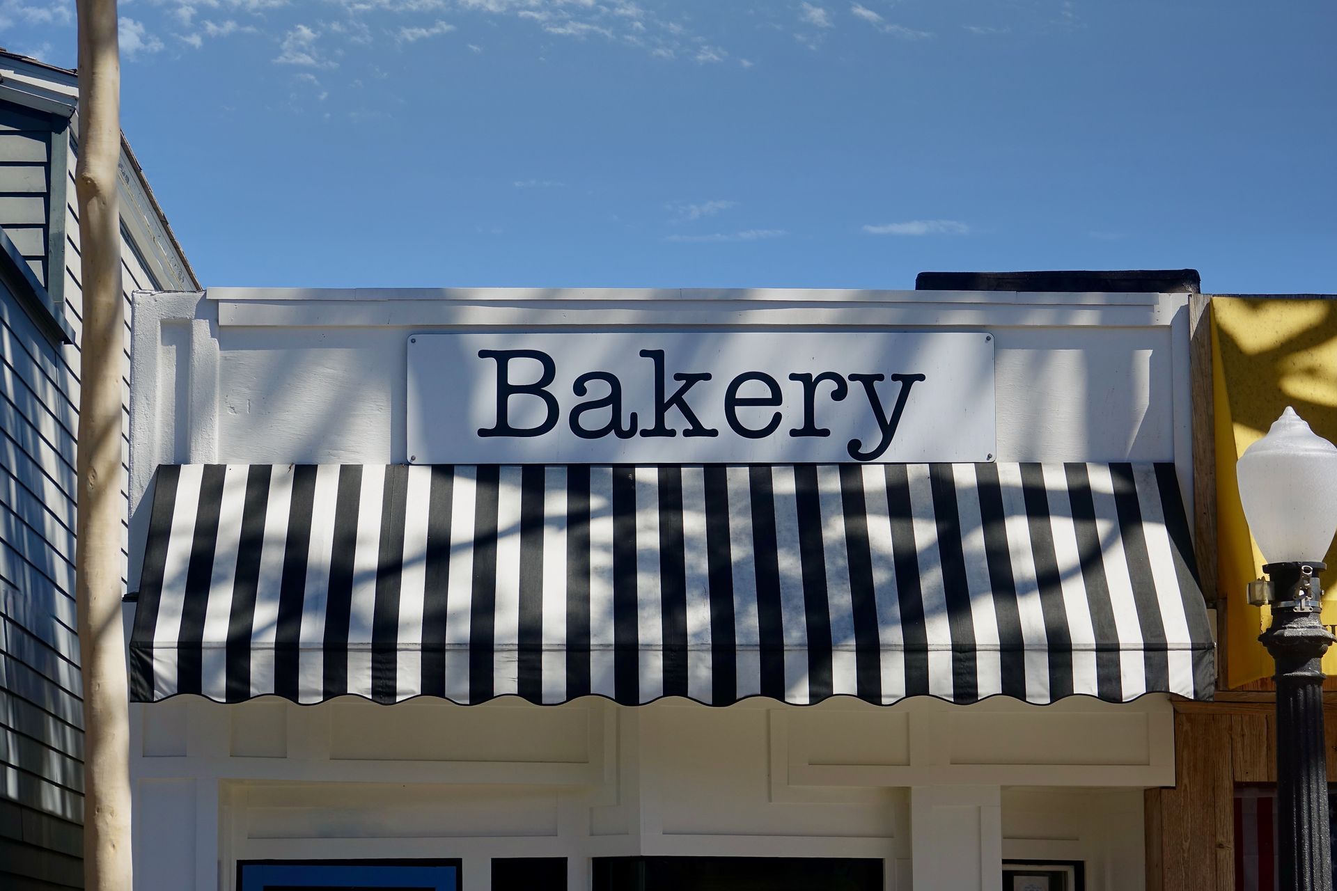 Storefront view featuring a striped awning and bold business sign. Storefront view featuring a striped awning and bold business sign.