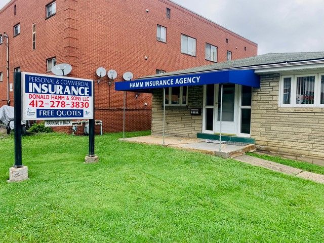 Insurance agency building with sign, awning, and grass lawn.