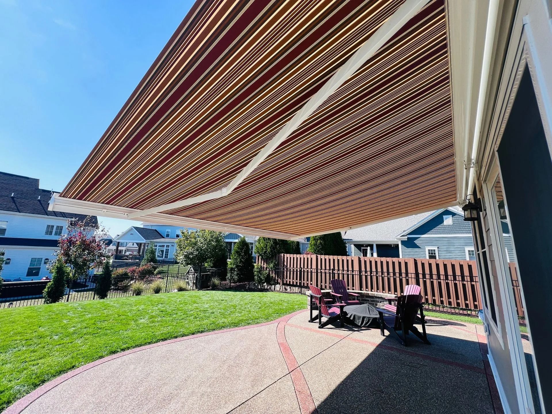 Retractable awning shades a patio with outdoor seating and a grassy yard