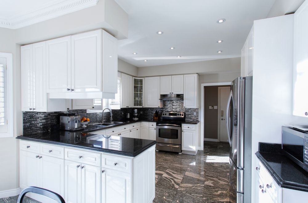 Bright White Kitchen With Black Countertops and Granite Flooring — Sunny Tiling Co in Mount Coolum, QLD