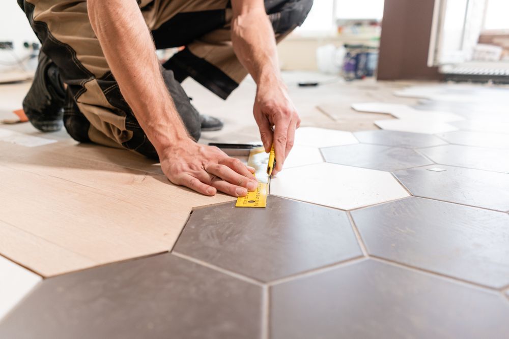 A Man is Kneeling on the Floor While Installing Tiles — Sunny Tiling Co in Mount Coolum, QLD