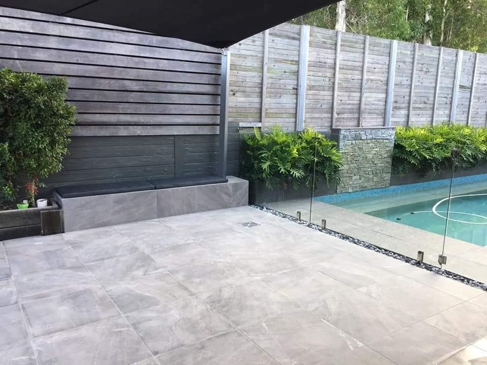 Patio With Pool, Grey Tiles, Glass Fence, Wooden Wall and Greenery — Sunny Tiling Co in Mount Coolum, QLD