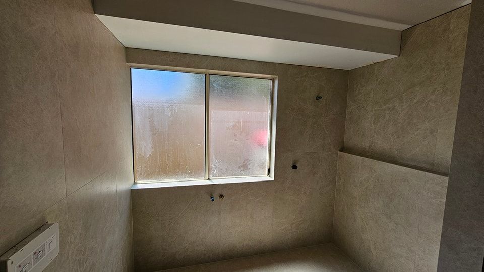 Empty room with window, covered with frosted glass. Tan tiled walls.