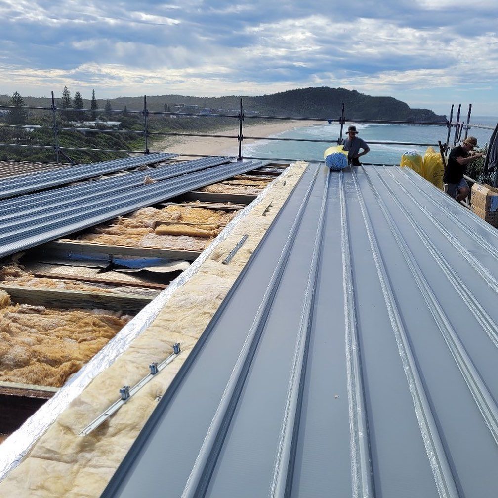 A Workers Installing a Gray Metal Roof — Coastline Building & Renovations In Tuncurry, NSW
