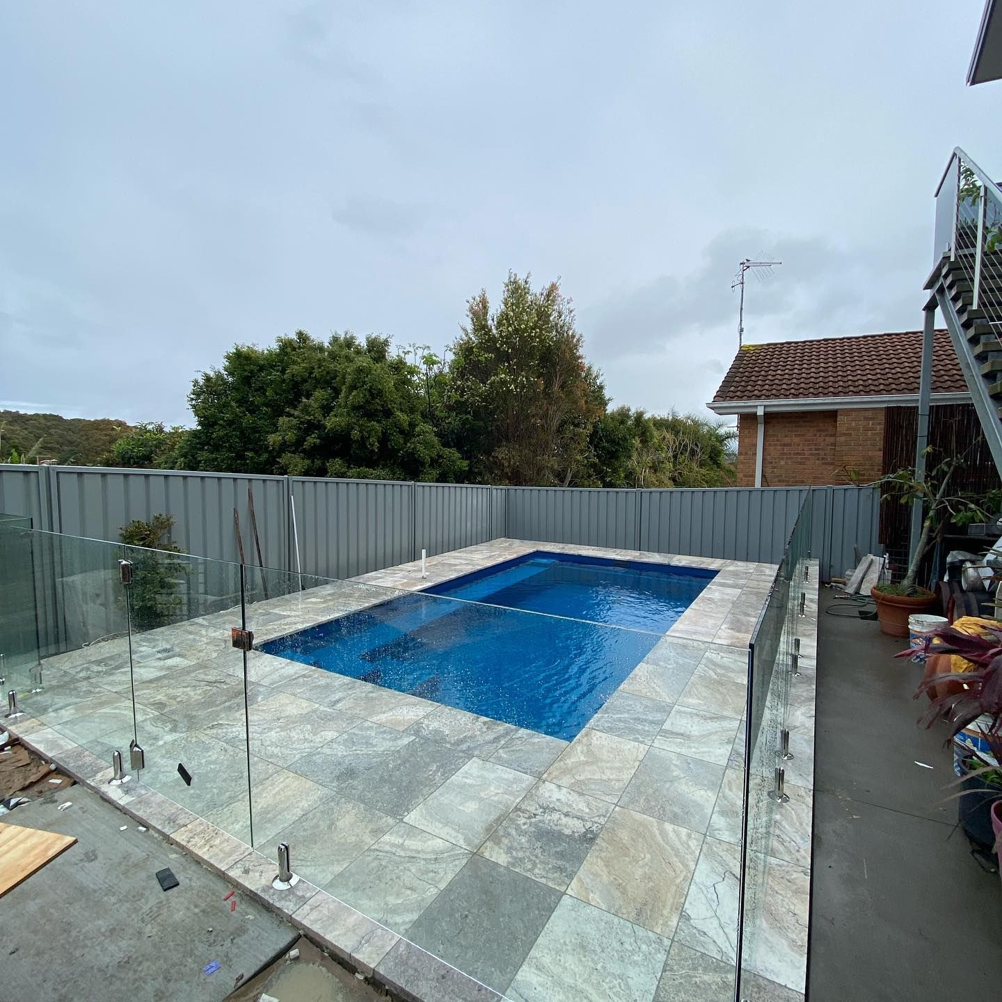 A Pool Surrounded by Grey Tile and Glass Fence — Coastline Building & Renovations In Boomerang Beach, NSW