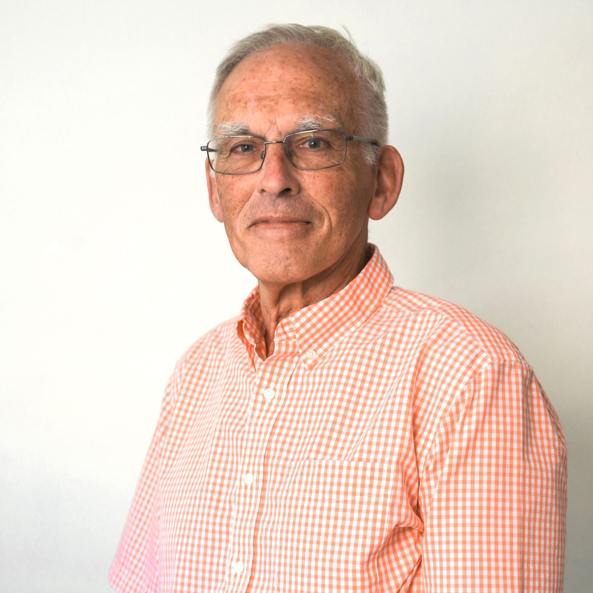 a man wearing glasses and an orange and white checkered shirt. Dr Peter Humphrey