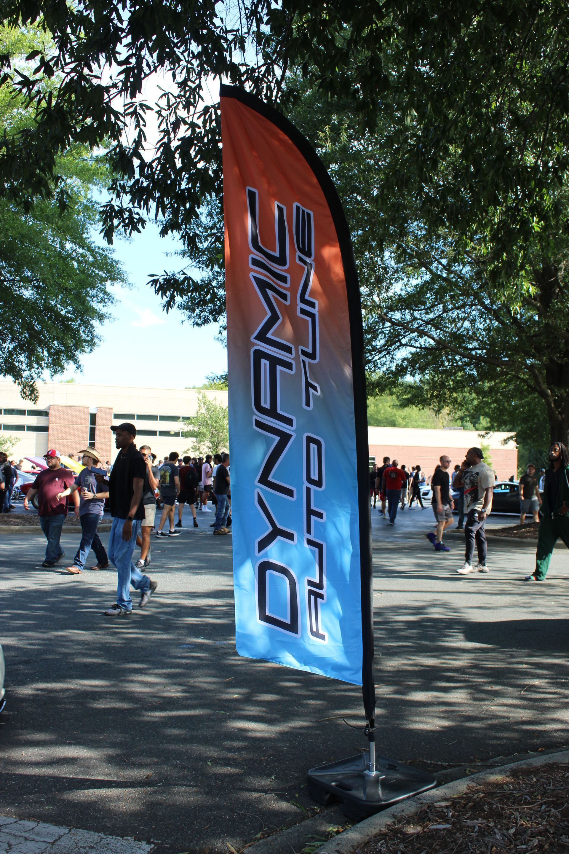 Orange-and-blue “DYNAMICS” banner at an outdoor event with people in the background
