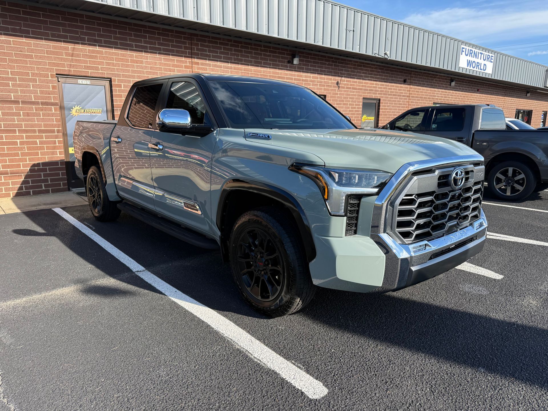 Gray pickup truck parked in a lot beside a brick building