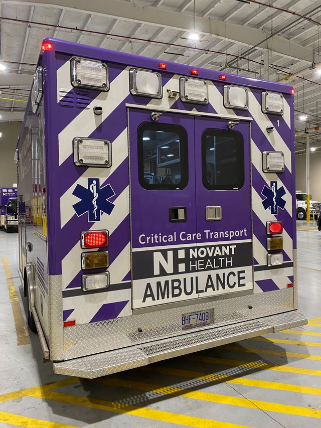 Purple-and-white Nacivant ambulance rear view in a garage, with red lights and Star of Life symbols