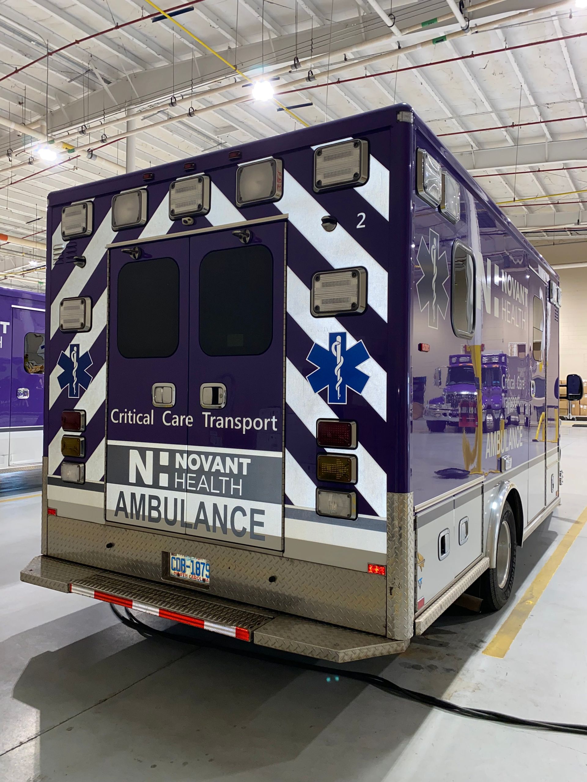 Rear view of a blue-and-white ambulance parked indoors in a garage or warehouse.