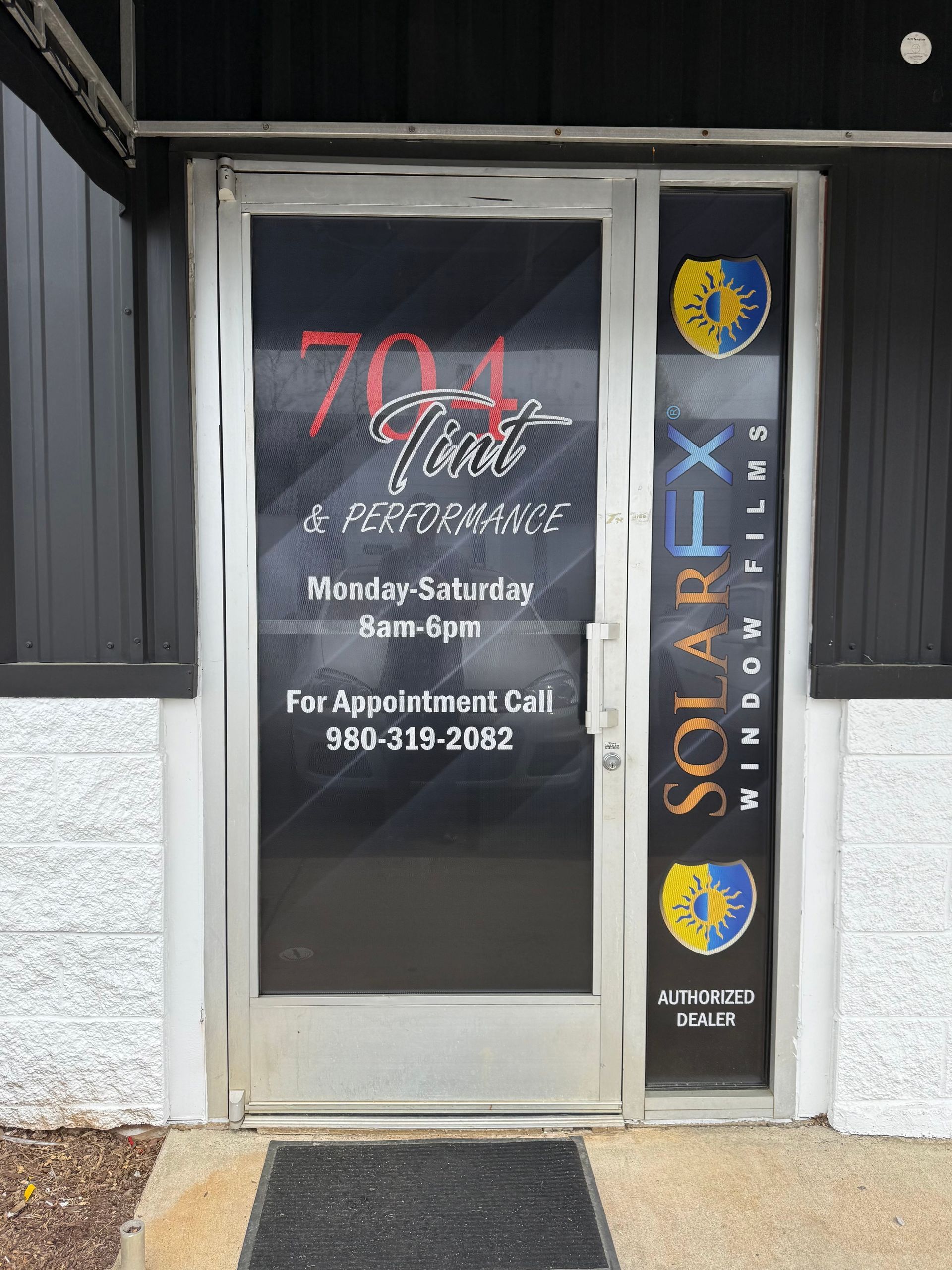 Storefront door with “704 Nails” sign, hours, phone number, and SolarFX window decal