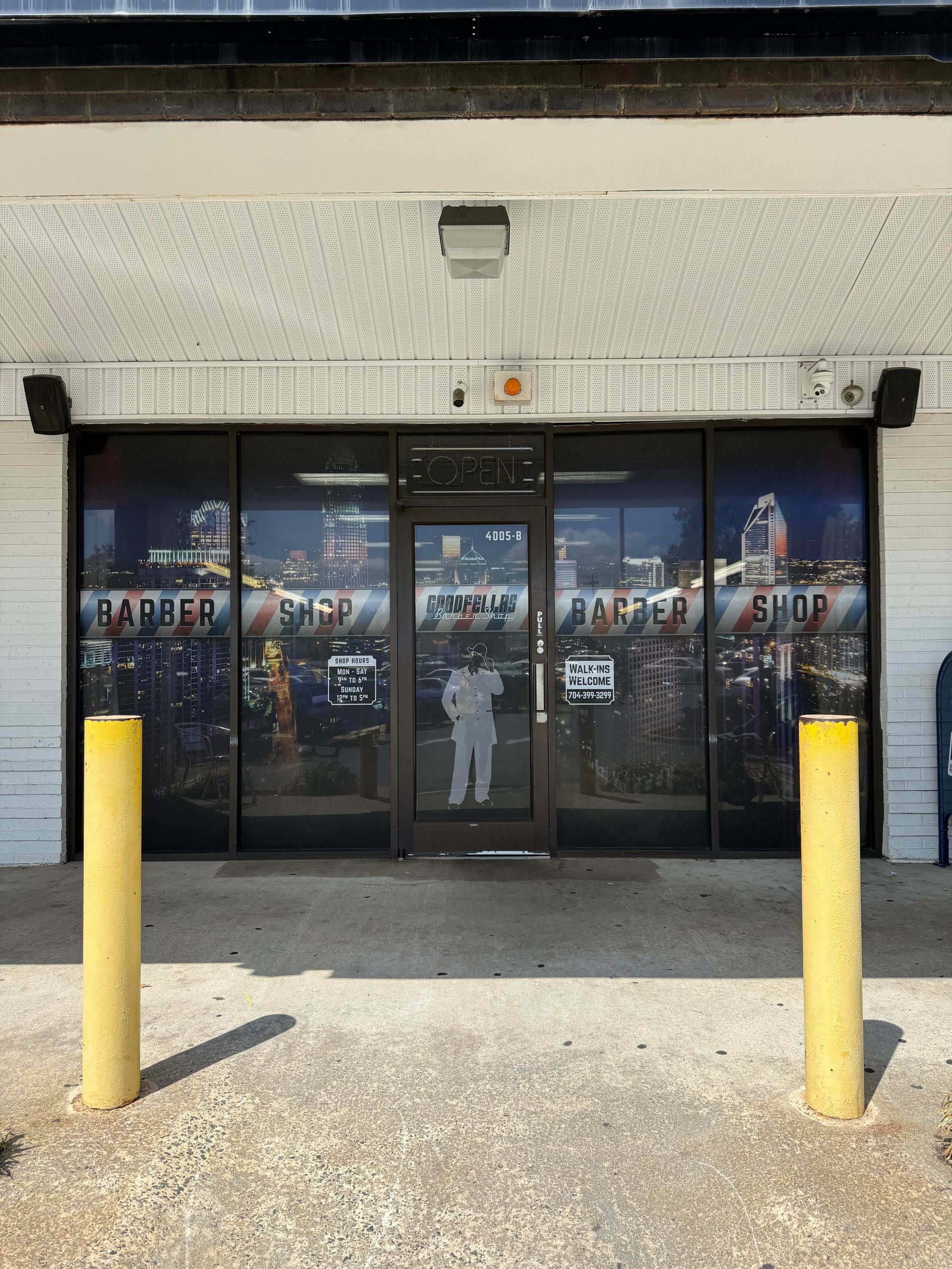 Storefront with glass double doors, city mural, and two yellow bollards outside.