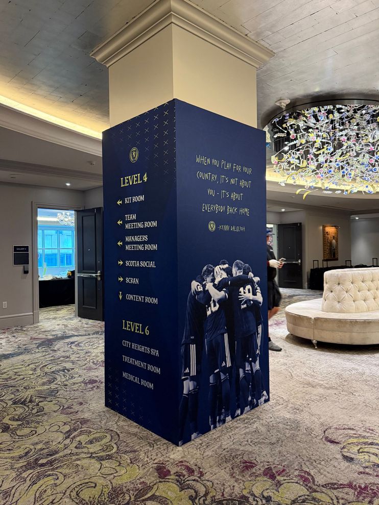 Blue event pillar with handwritten white notes in a confetti-covered lobby near a white sofa