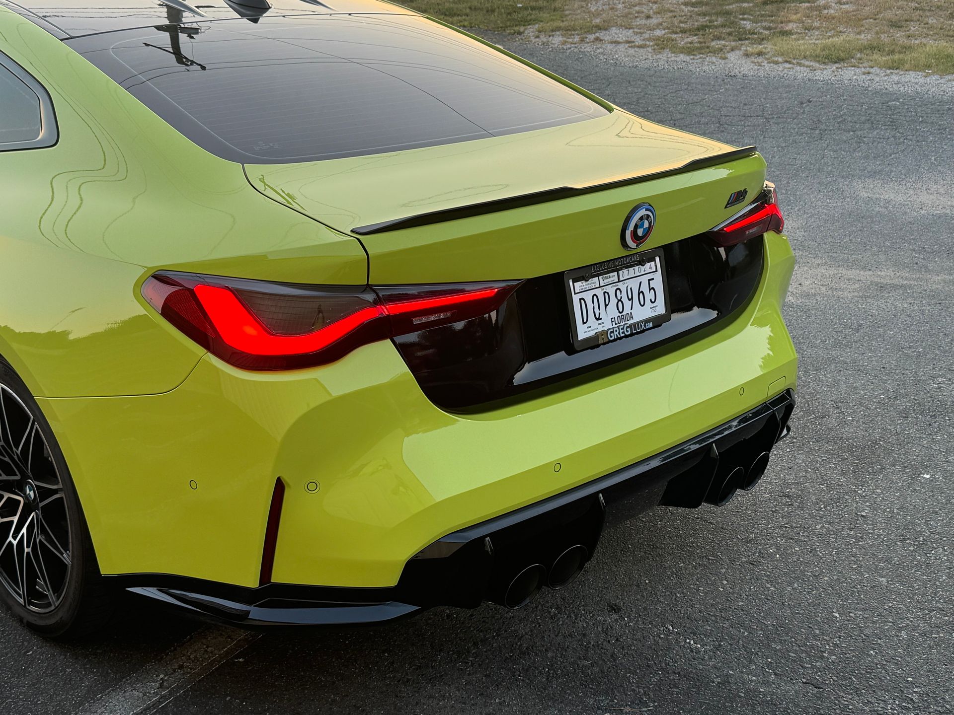 Rear view of a lime-green BMW sedan parked on wet pavement.