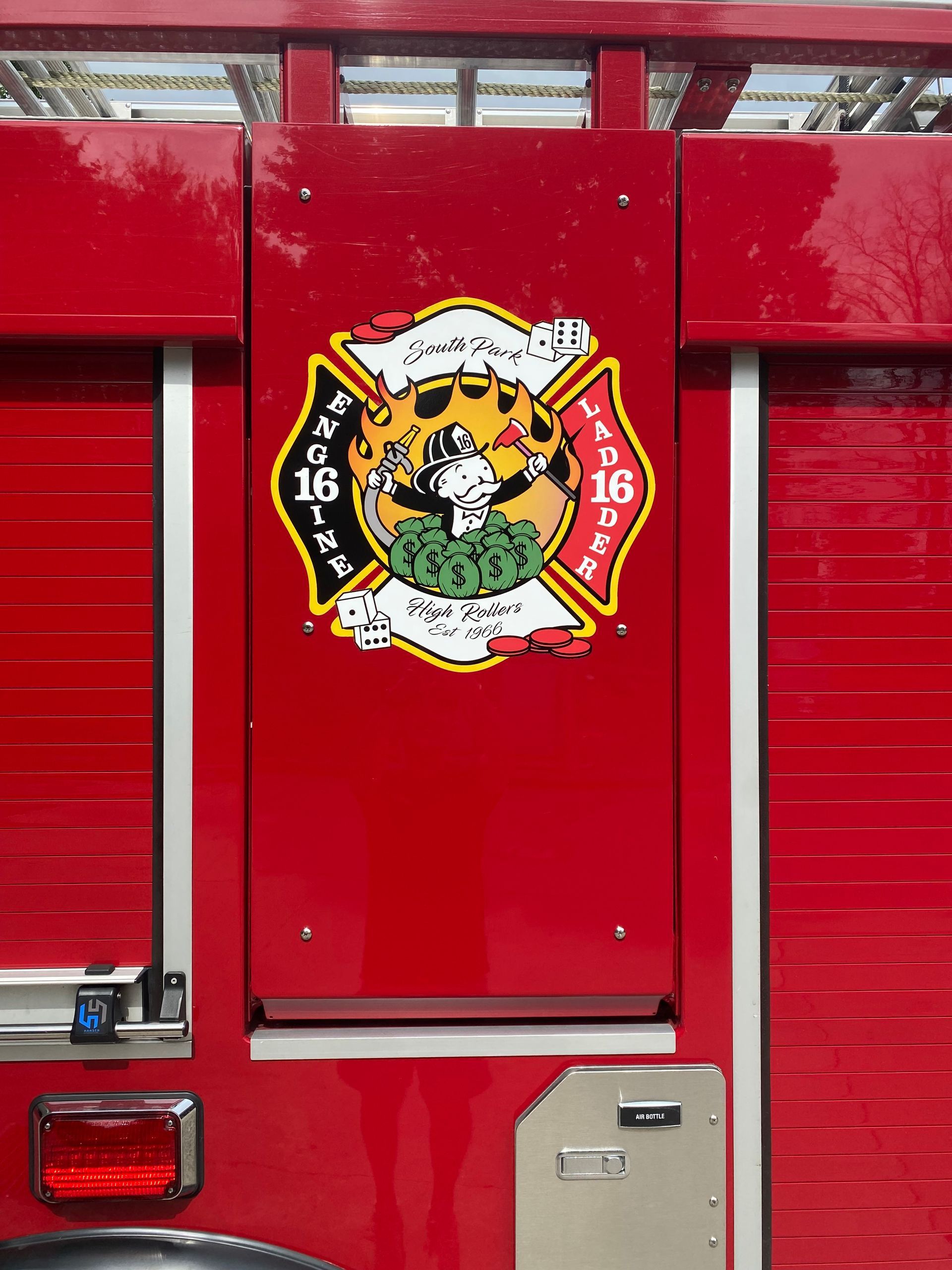 Red fire truck side panel with a firefighters’ emblem in red, black, white, and gold.
