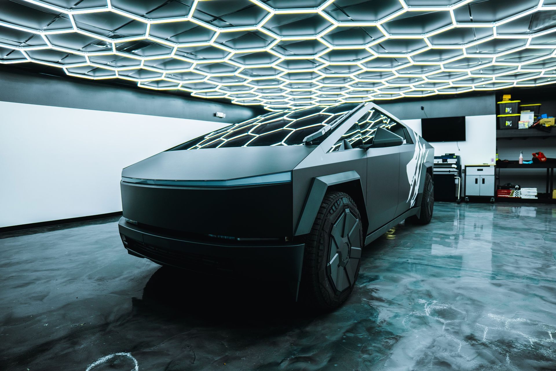 Tesla Cybertruck in a modern garage with hexagonal ceiling lights and a polished floor