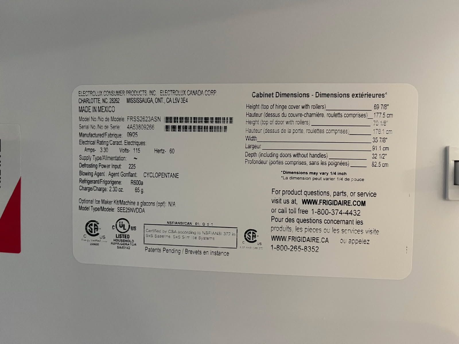 White appliance specification label with black text and barcodes on a gray surface