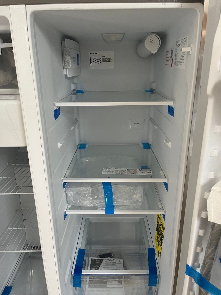 Open white utility cabinet with empty shelves, blue tape, and a round control knob inside.