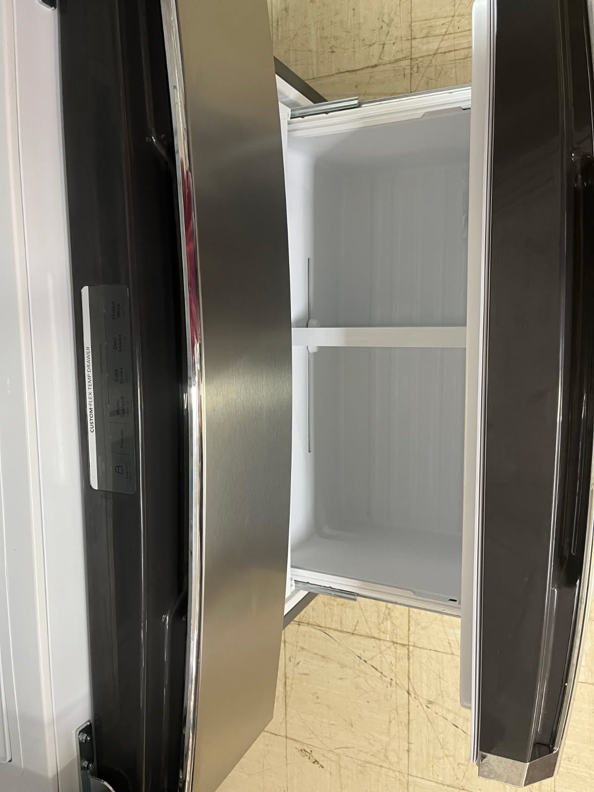 Open refrigerator with shelves inside and a stainless steel door in a kitchen.