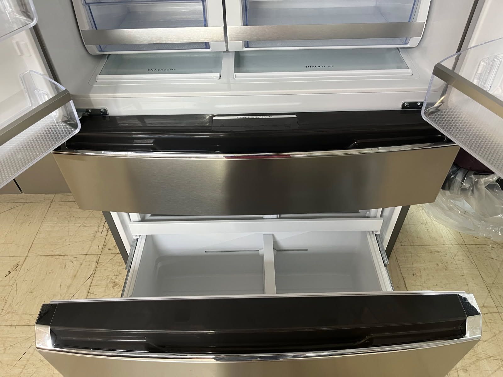 Stainless steel shopping cart with black padded handle and lower shelf in a store aisle