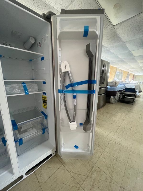 Open refrigerator with shelves and blue tape in a store aisle, with a display of long tools on the door.