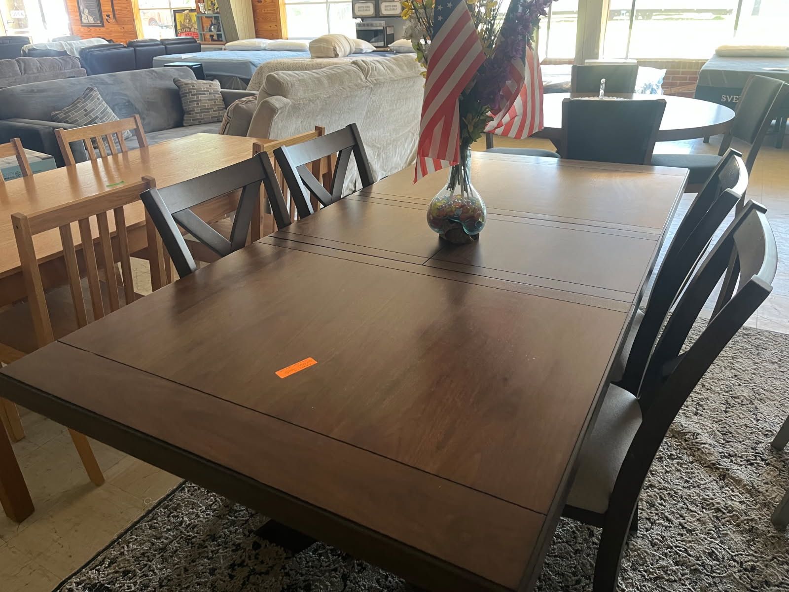 Wooden dining table with chairs in a bright, casual dining room, with an American flag centerpiece.