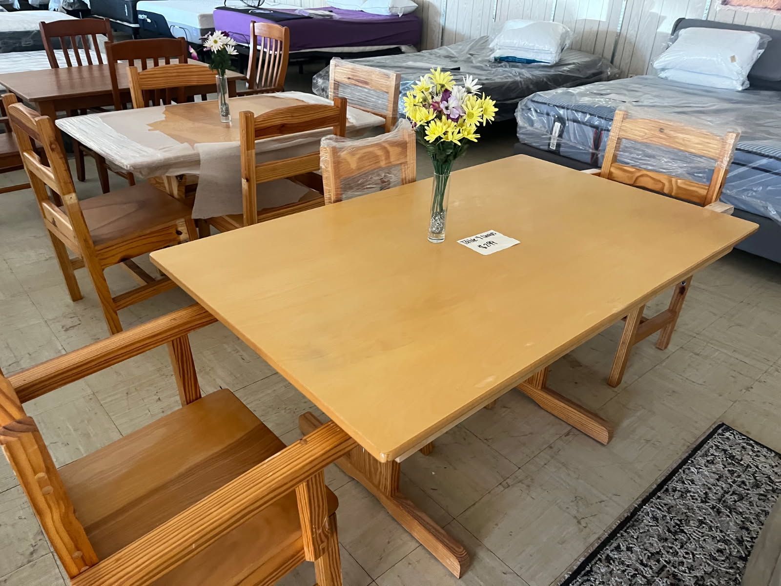 Dining room with wooden tables and chairs, one table topped with a small vase of flowers.
