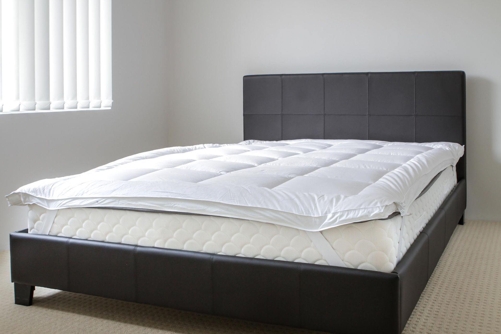 Modern dark gray upholstered bed with white bedding in a bright, minimal bedroom