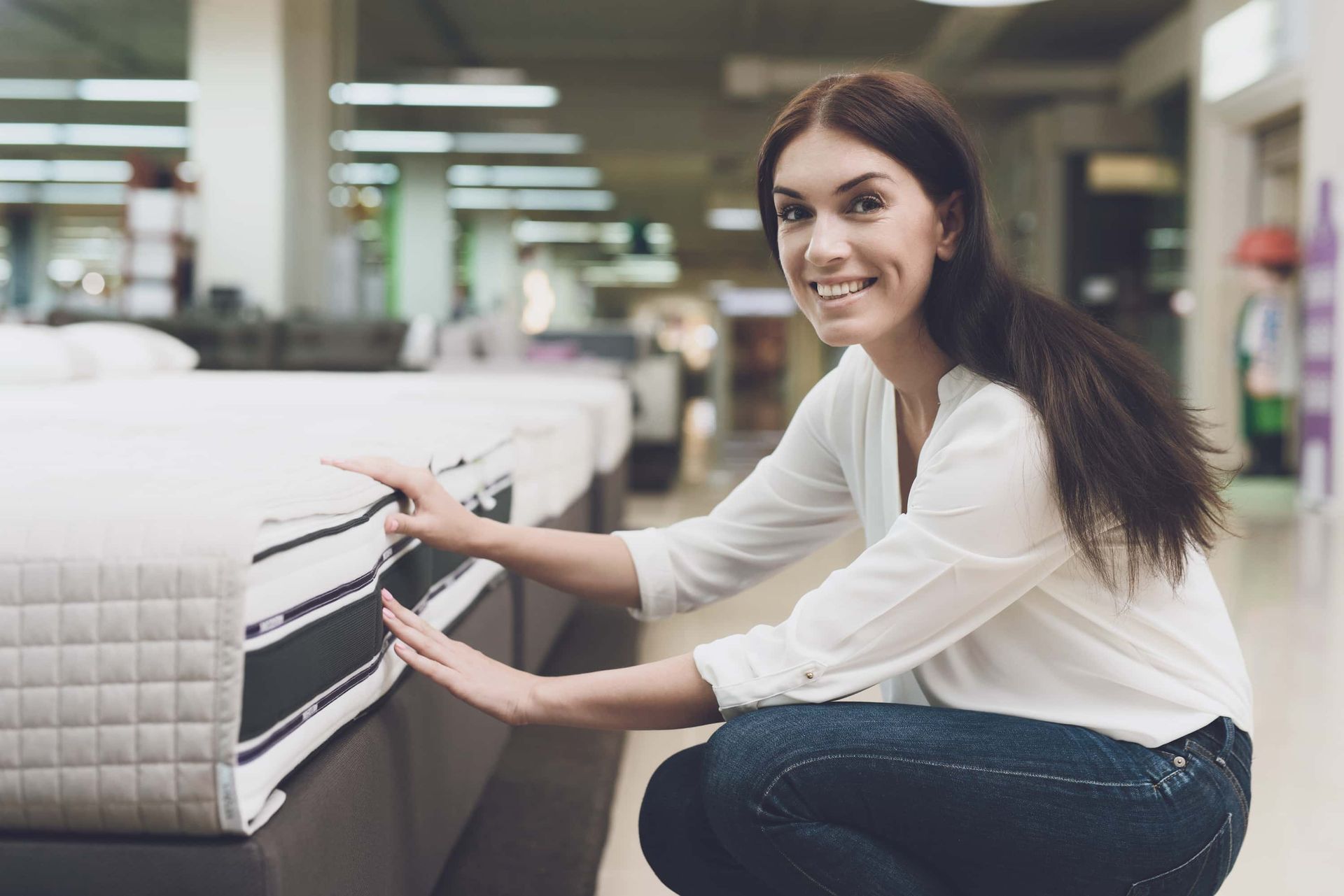 Woman smiling while testing a mattress in a store showroom