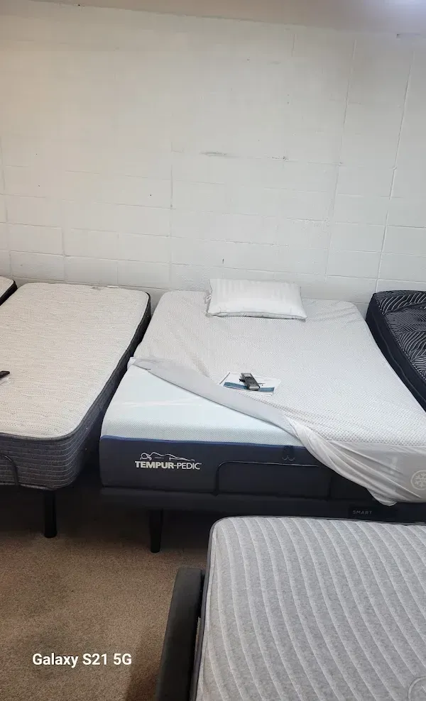 Three single beds with white bedding in a plain room, with a phone on the middle bed.