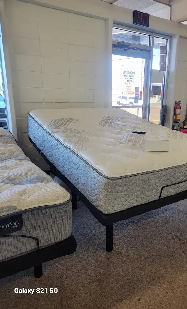 Mattresses displayed in a showroom, with a doorway and wall in the background.