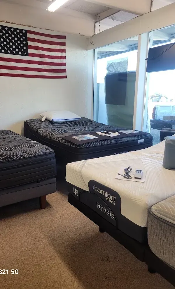 Air mattresses arranged in a bright room with an American flag on the wall and a TV by the window.