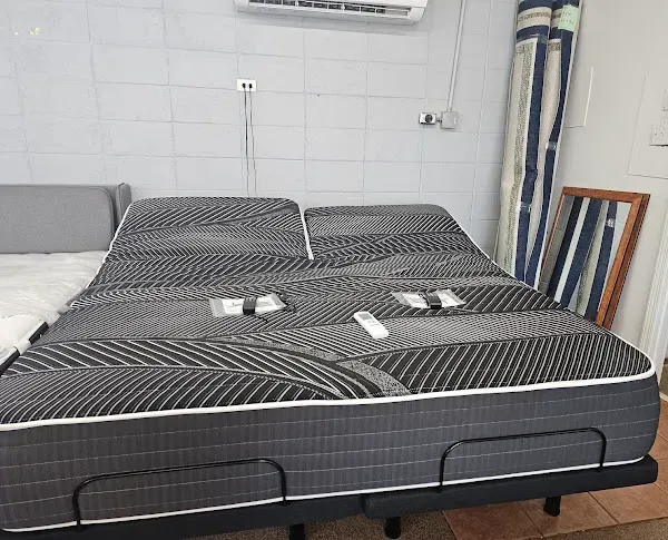 Bedroom with a gray bed made up in black-and-white bedding, folded towels, and a wall-mounted air conditioner.