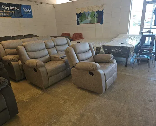 Furniture showroom with gray recliners, chairs, and sofas on a concrete floor under posters and a map.