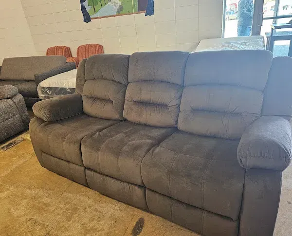 Dark gray reclining sofa in a living room with orange chairs and wall art.