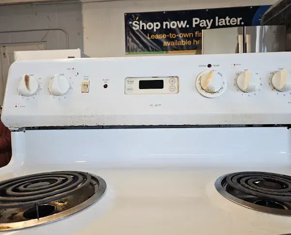 White electric stove with four coil burners and control knobs, seen in a kitchen