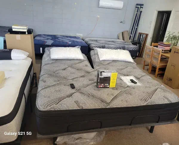 Bedroom with a black bed, gray comforter, and pillows, plus furniture and boxed items around it.