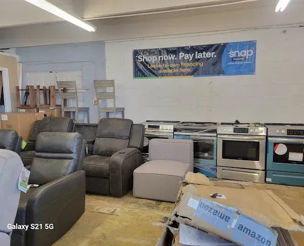 Furniture store with recliners, a loveseat, and boxed items on the floor under a Snap Finance banner.